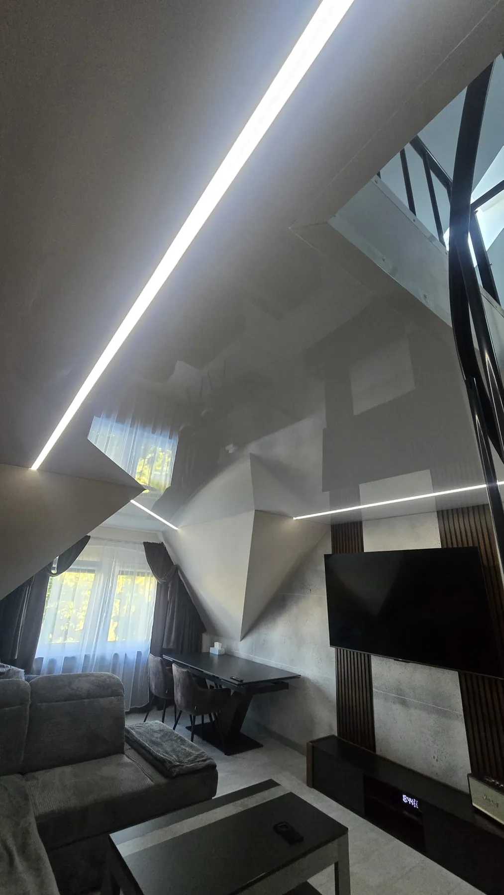 Szary lustrzany sufit napinany z liniami LED w salonie